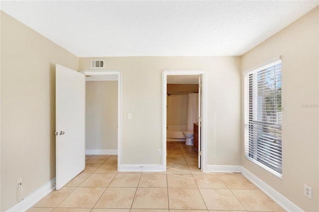 unfurnished bedroom with light tile patterned flooring, baseboards, and visible vents