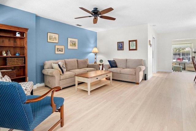 living room featuring visible vents, a textured ceiling, light wood-style floors, baseboards, and ceiling fan