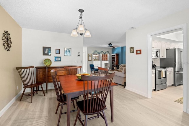 dining space featuring light wood finished floors, a textured ceiling, baseboards, and ceiling fan