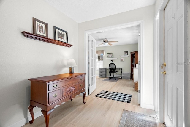 corridor featuring light wood-style flooring, french doors, and baseboards