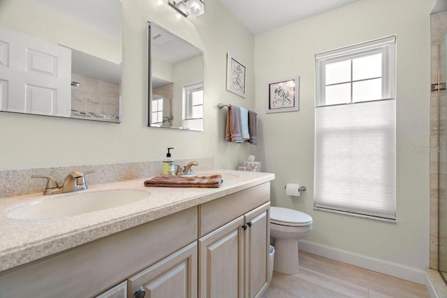 full bathroom featuring toilet, a sink, wood finished floors, double vanity, and baseboards