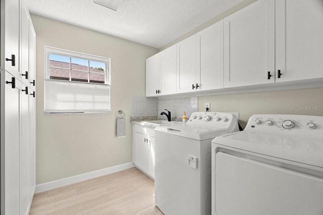 laundry area with a sink, baseboards, light wood-style floors, cabinet space, and separate washer and dryer