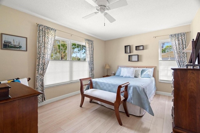 bedroom with light wood-style flooring, a textured ceiling, baseboards, and ceiling fan