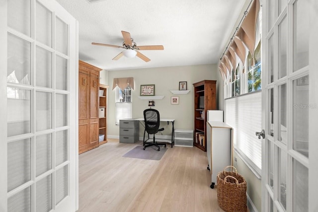 office area with light wood-type flooring, a textured ceiling, french doors, baseboards, and ceiling fan