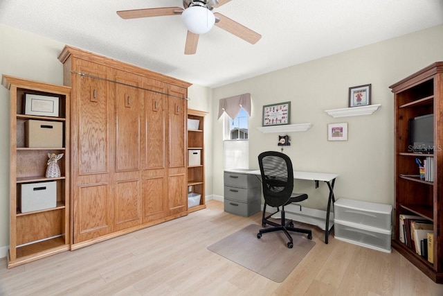 office space featuring light wood-style flooring, a textured ceiling, baseboards, and a ceiling fan