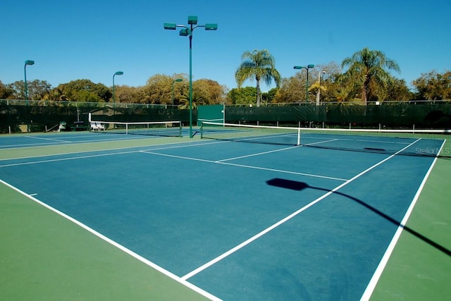 view of tennis court with community basketball court and fence