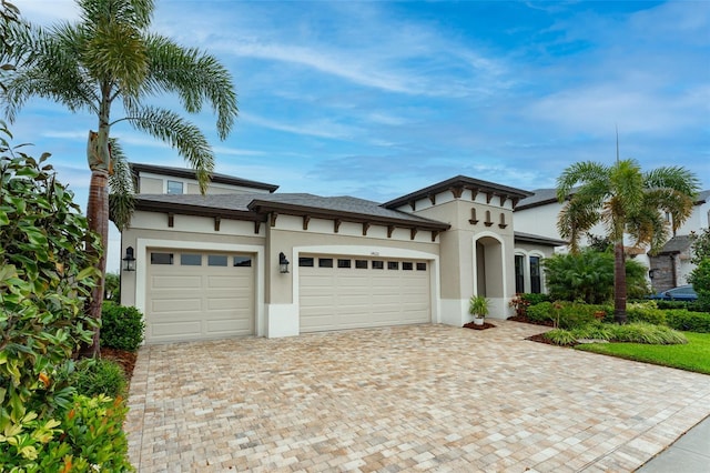 view of front of house featuring stucco siding, an attached garage, and decorative driveway