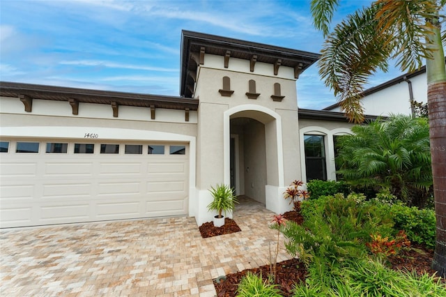 view of front facade with decorative driveway, an attached garage, and stucco siding