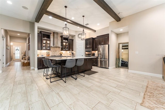 kitchen with tasteful backsplash, wall chimney range hood, light countertops, a kitchen breakfast bar, and appliances with stainless steel finishes