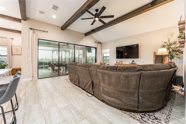 living area featuring a wealth of natural light, visible vents, lofted ceiling with beams, and a ceiling fan