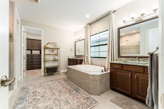 full bath with a shower stall, a textured ceiling, a garden tub, and a sink