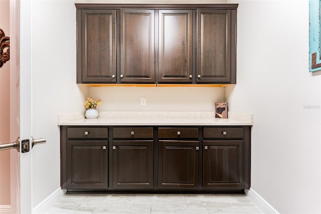 kitchen with dark brown cabinets, light countertops, and baseboards