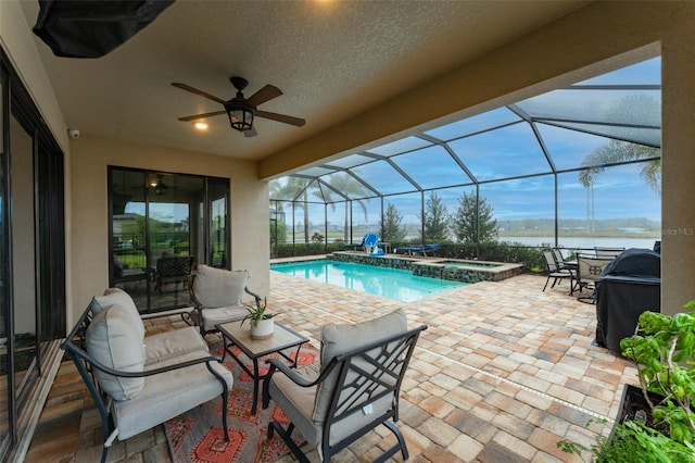 view of swimming pool featuring a pool with connected hot tub, ceiling fan, a water view, a lanai, and a patio area