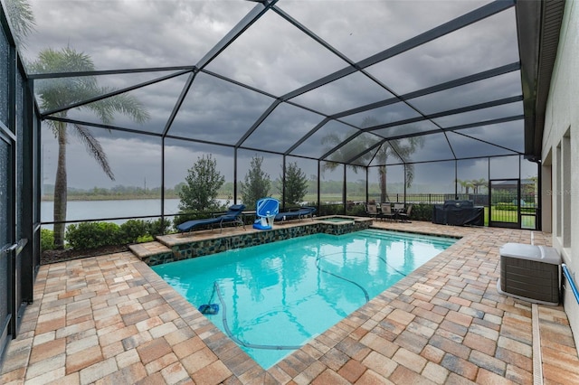 view of swimming pool with glass enclosure, a water view, a pool with connected hot tub, and a patio area