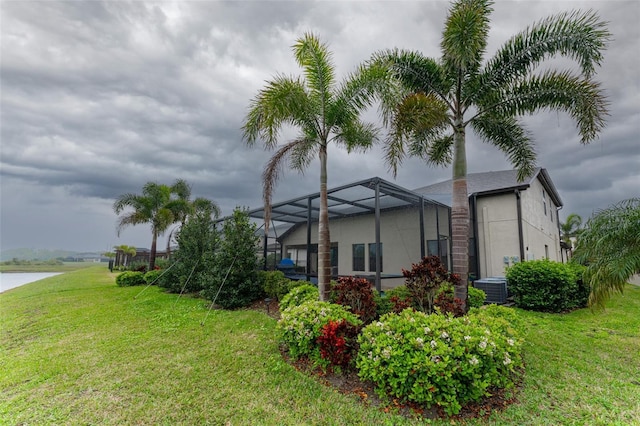 exterior space featuring glass enclosure, a yard, stucco siding, a water view, and central air condition unit