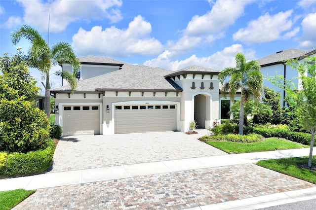 view of front of house featuring stucco siding, decorative driveway, and a garage