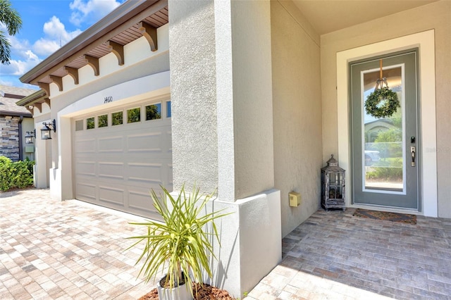 view of exterior entry featuring stucco siding and an attached garage