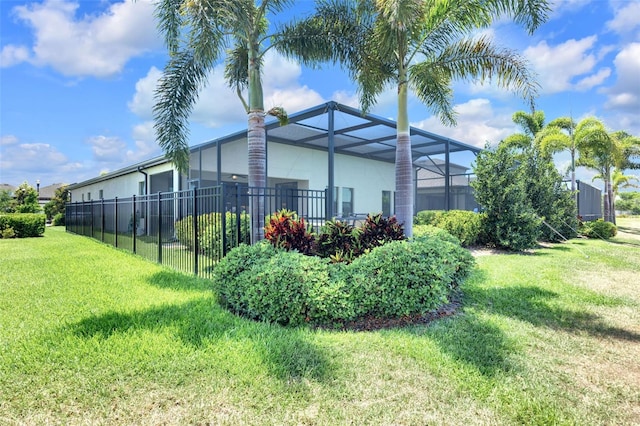 view of property exterior featuring a lanai, a yard, and fence