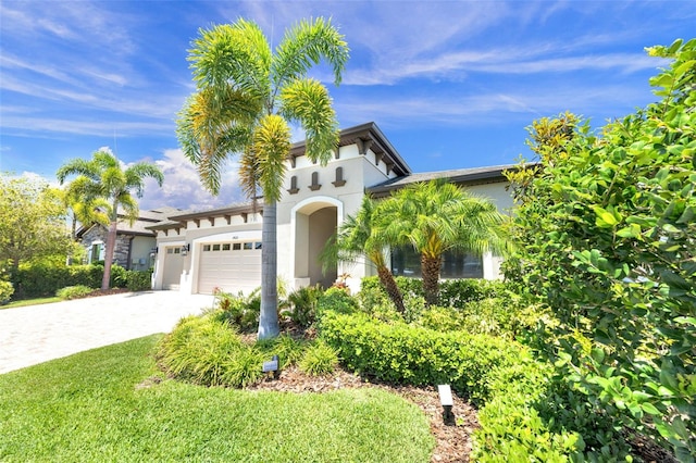 mediterranean / spanish-style house with decorative driveway, a front lawn, a garage, and stucco siding