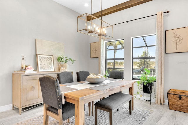 dining area with light wood-style floors, a high ceiling, a notable chandelier, and baseboards