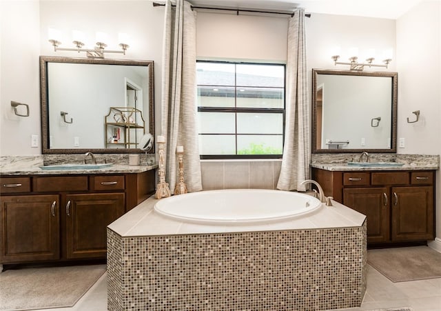 bathroom featuring two vanities, a garden tub, and a sink