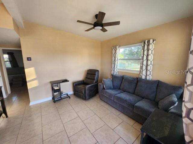 living room with baseboards, ceiling fan, and light tile patterned flooring