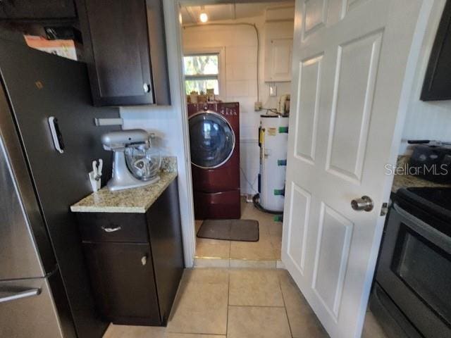 washroom with laundry area, light tile patterned floors, water heater, and washer / dryer