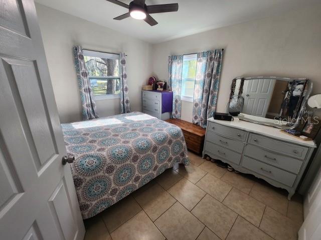 bedroom featuring multiple windows, a ceiling fan, and light tile patterned floors