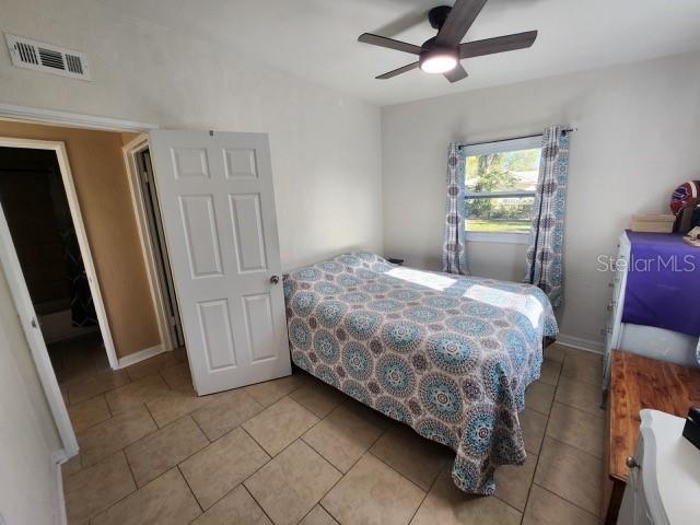 bedroom featuring light tile patterned floors, visible vents, baseboards, and a ceiling fan