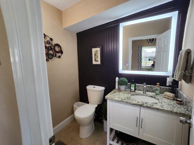 bathroom with baseboards, toilet, vanity, and tile patterned flooring