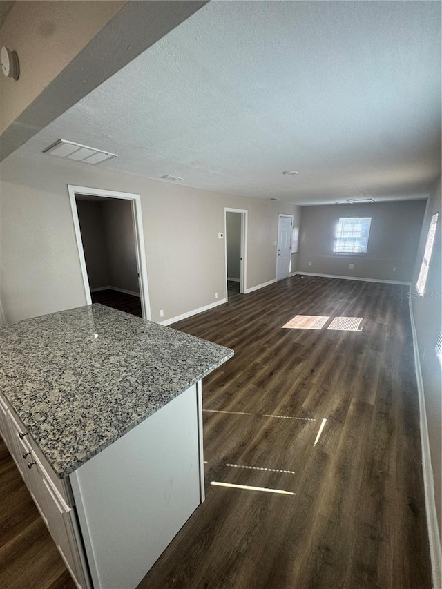 living area with visible vents, baseboards, dark wood-type flooring, and a textured ceiling