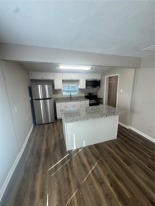 kitchen featuring a sink, baseboards, stainless steel appliances, white cabinetry, and dark wood-style flooring