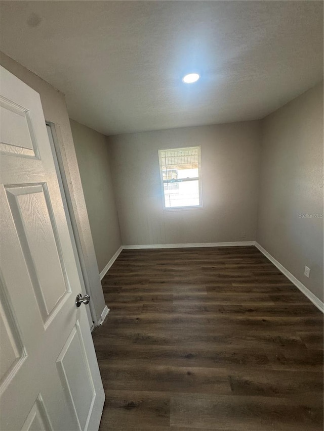 unfurnished room with dark wood-style floors and baseboards