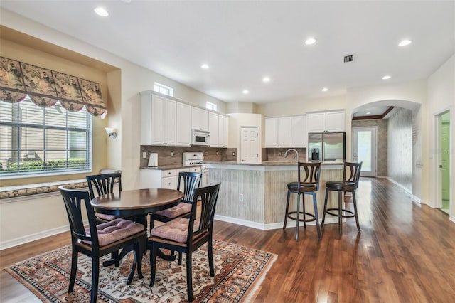 dining room with visible vents, baseboards, recessed lighting, arched walkways, and dark wood-style flooring