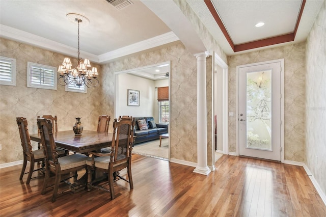 dining space featuring visible vents, baseboards, ornamental molding, hardwood / wood-style floors, and ornate columns