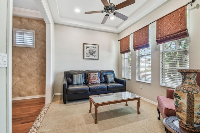 living room with light wood finished floors, baseboards, recessed lighting, a raised ceiling, and a ceiling fan