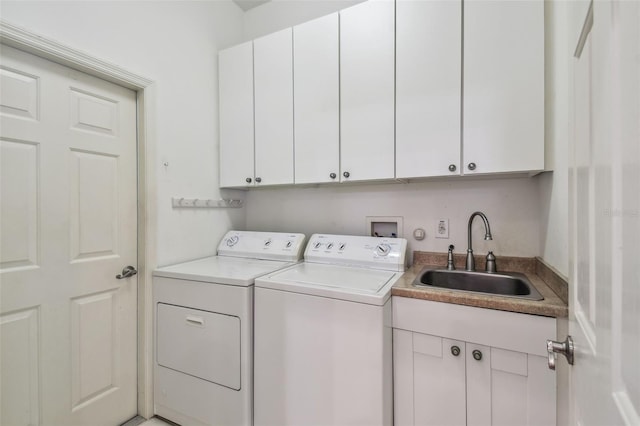 clothes washing area with cabinet space, washer and dryer, and a sink