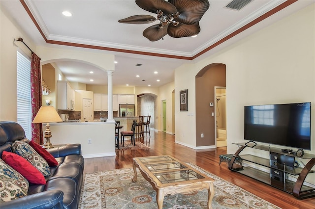 living area with wood finished floors, a ceiling fan, visible vents, arched walkways, and ornamental molding