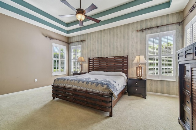 bedroom featuring baseboards, a raised ceiling, carpet, and a ceiling fan