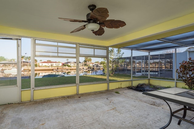 unfurnished sunroom featuring a wealth of natural light, a water view, and ceiling fan