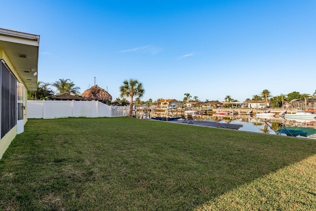 view of yard featuring a water view, a boat dock, and fence