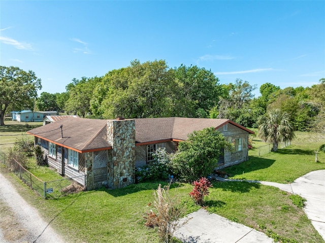 view of front facade featuring a front lawn, fence, driveway, and a chimney