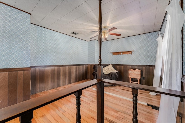 interior space with a wainscoted wall, visible vents, a ceiling fan, and wallpapered walls