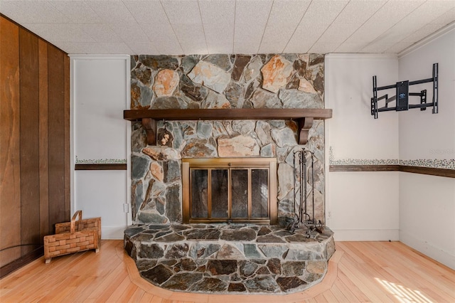 room details featuring a stone fireplace, wood finished floors, and baseboards