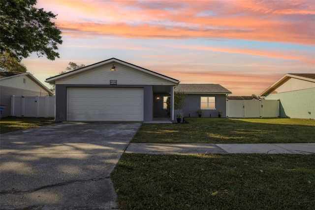 ranch-style house featuring a lawn, driveway, a gate, fence, and an attached garage