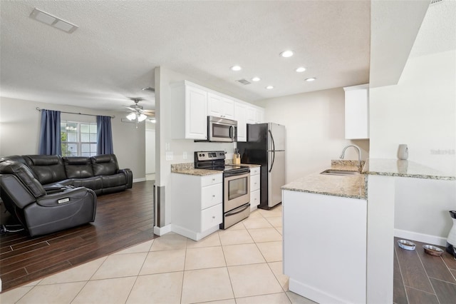 kitchen featuring light stone countertops, visible vents, a sink, appliances with stainless steel finishes, and open floor plan