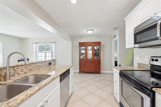 kitchen featuring a sink, a textured ceiling, appliances with stainless steel finishes, and white cabinets