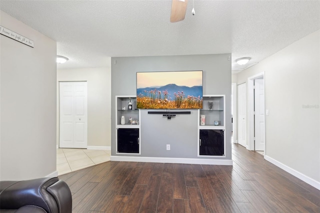 unfurnished living room with baseboards, a textured ceiling, and wood finished floors