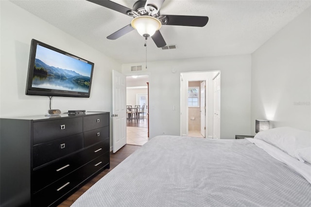 bedroom with dark wood-style floors, visible vents, and ensuite bathroom