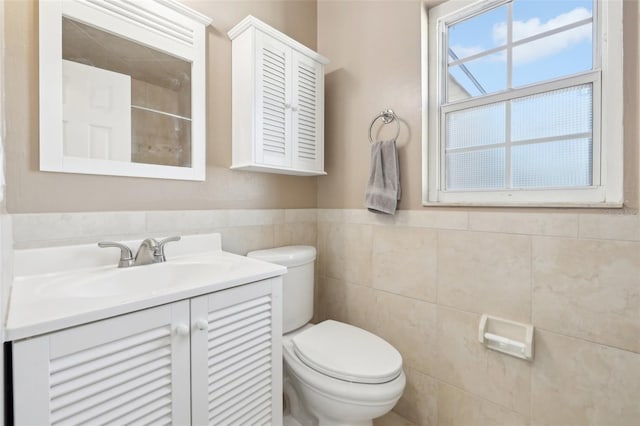 bathroom with vanity, walk in shower, wainscoting, tile walls, and toilet